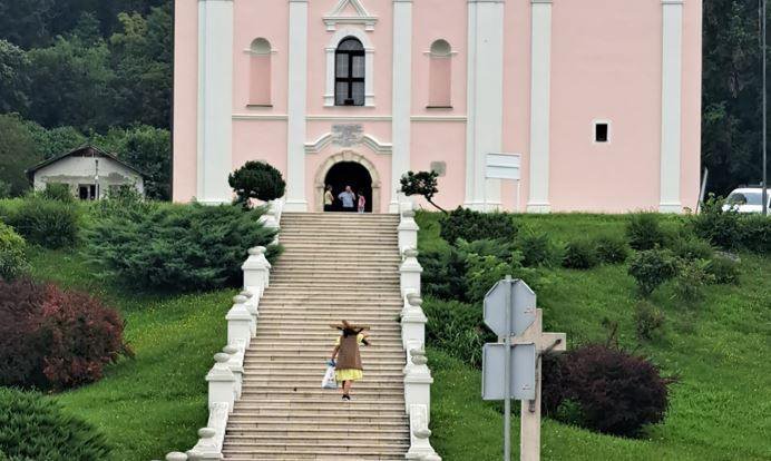 Fotografija: Žena s drvenim križem na leđima ispred crkve/Foto: Snimila čitateljica